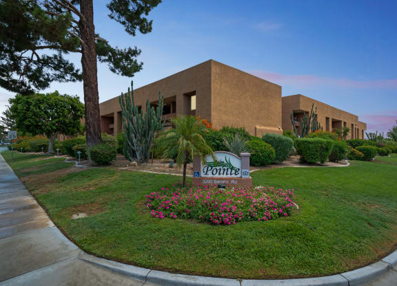 a building with a sign in front of a lawn with flowers