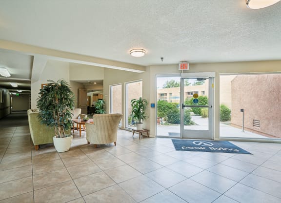 a lobby with chairs and a rug in front of a glass door