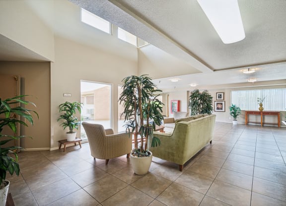 a lobby with a couch and chairs and plants