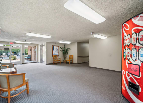 a large room with chairs and a coke vending machine