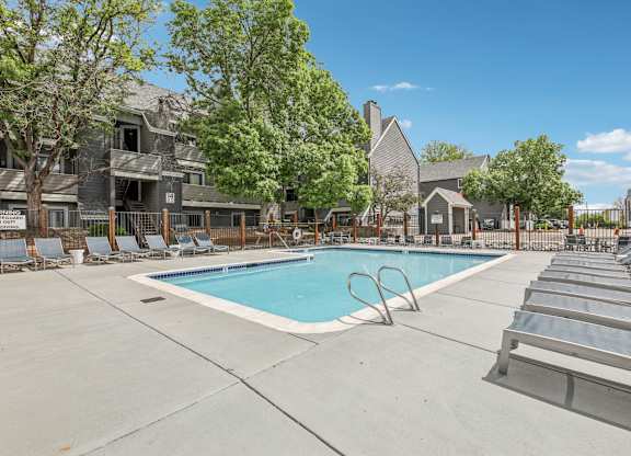 A swimming pool surrounded by lounge chairs and trees.