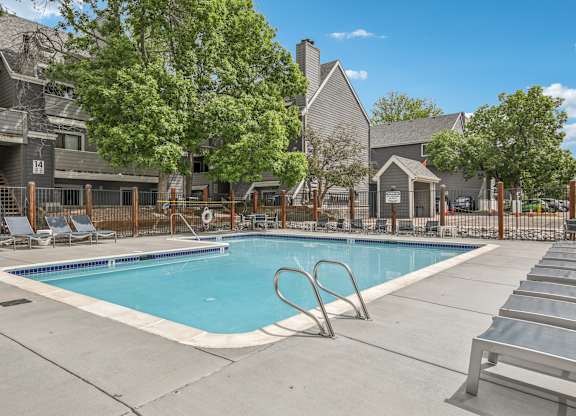 A swimming pool surrounded by lounge chairs and trees.