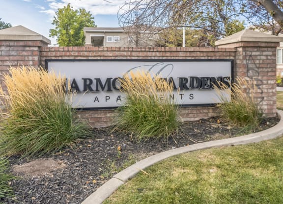 a sign apartments in front of a brick wall with tall grass