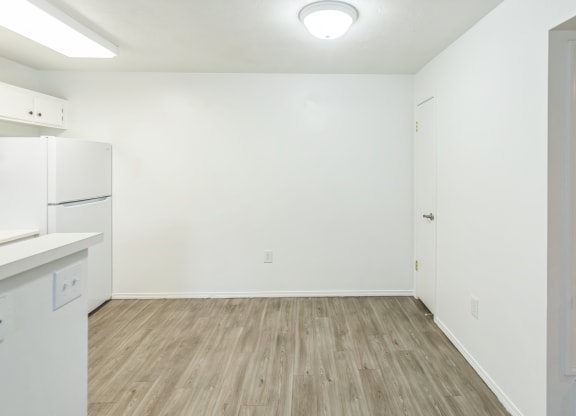 an empty room with white walls and a white refrigerator