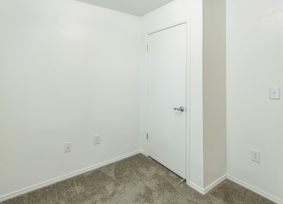 a bedroom with white walls and carpet and a white door