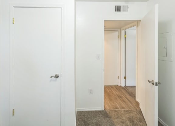 a bedroom with white walls and a door to a hallway