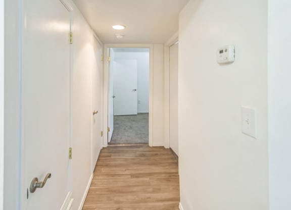 a long hallway with white walls and a wood floor