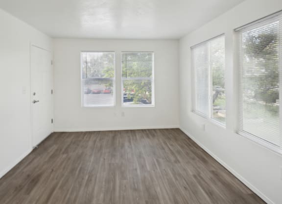 an empty living room with three windows and wood floors