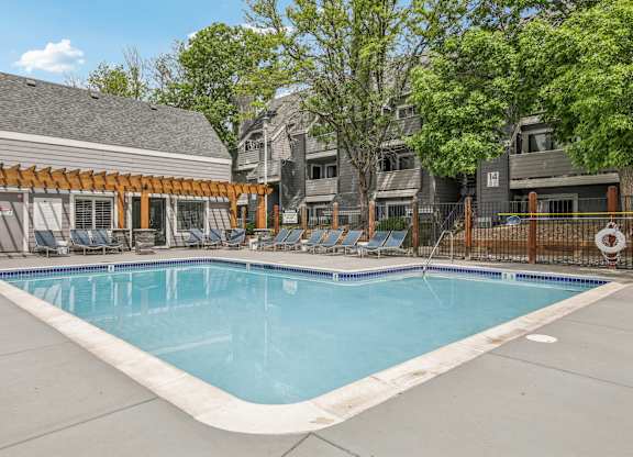 A swimming pool surrounded by lounge chairs and trees.