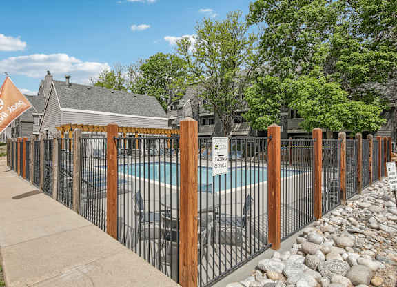 A pool surrounded by a black fence with a sign that says "SAFETY FIRST" on it.