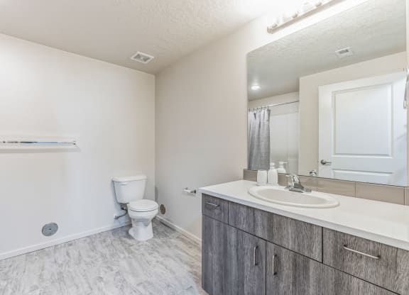 A bathroom with a toilet, sink, and mirror.