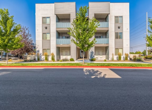 A modern apartment building with a parking lot in front.