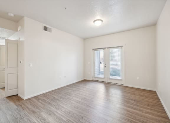 the living room of an apartment with white walls and wood floors