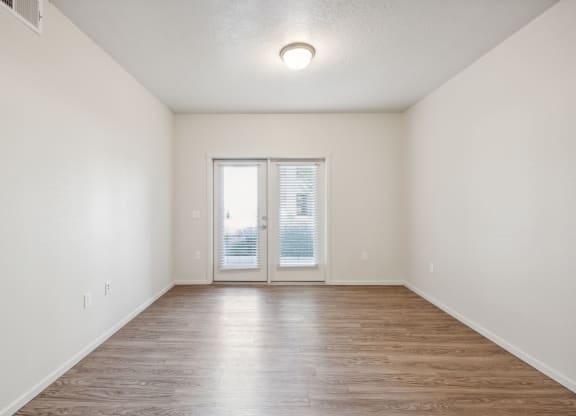A room with a sliding glass door and wood flooring.