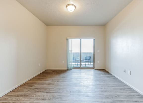 A room with wooden flooring and a sliding glass door.