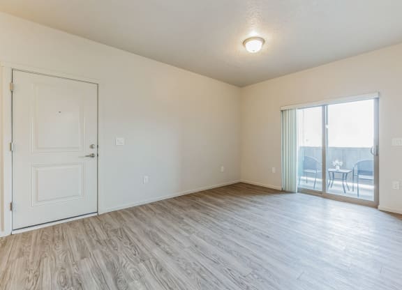 A room with a white door and a sliding glass door leading to a balcony.
