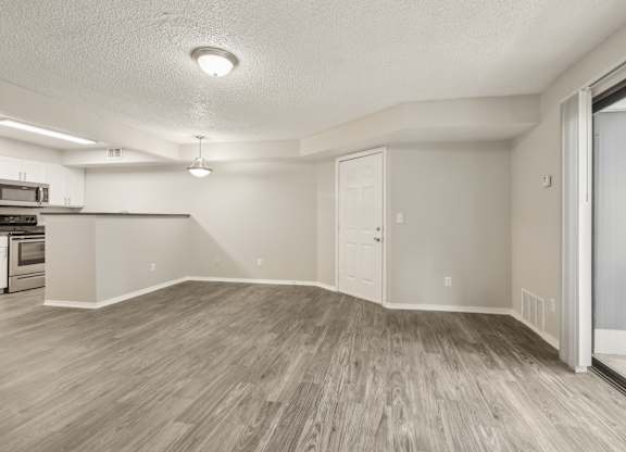 A spacious room with wooden flooring and white walls.