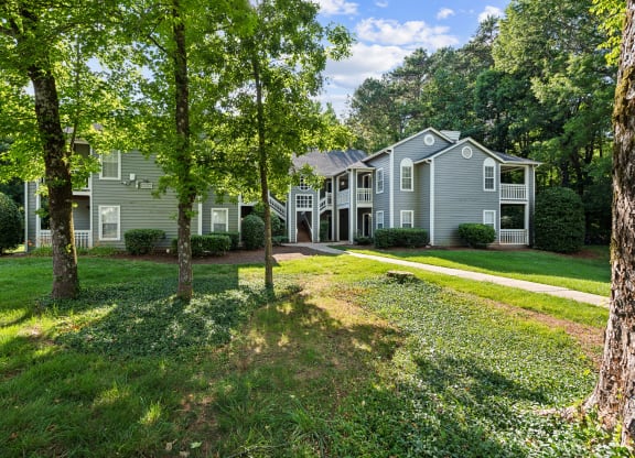 the front of the house with trees and grass