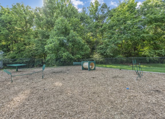 a fenced in dog park with trees in the background