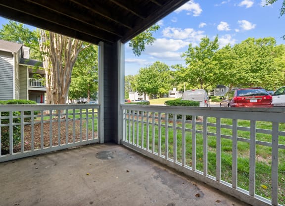 the view from the porch of an apartment building with cars parked in the yard