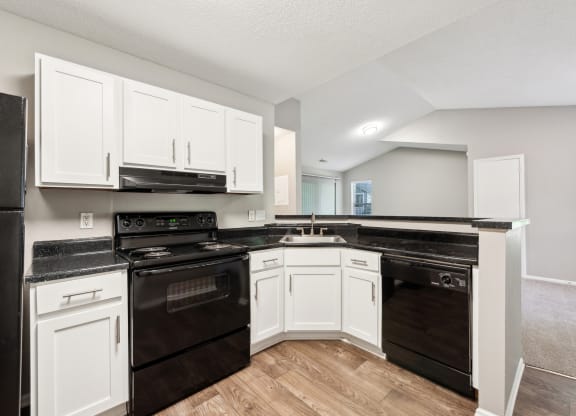 an empty kitchen with white cabinets and black appliances