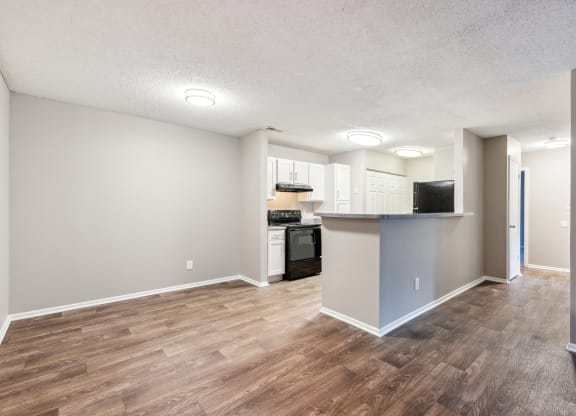 an empty living room and kitchen with a wood floor
