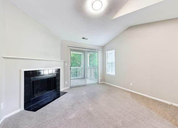 an empty living room with a fireplace and a balcony
