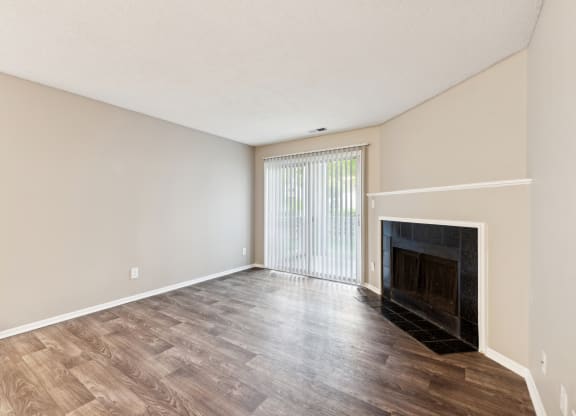 an empty living room with a fireplace and wood flooring