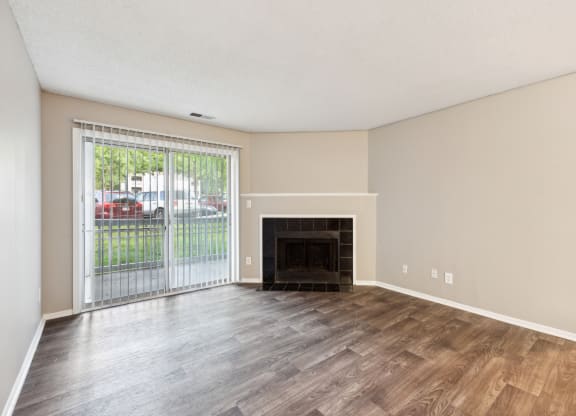 an empty living room with a fireplace and a sliding glass door