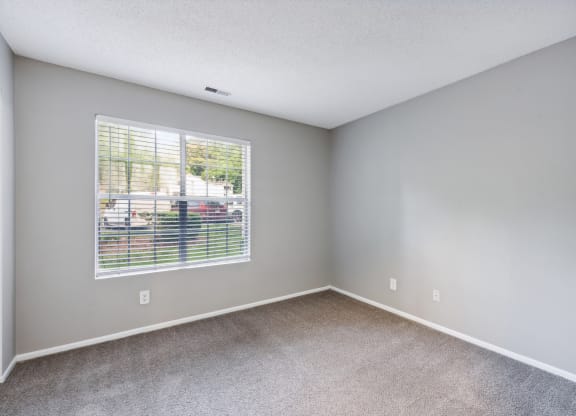 an empty bedroom with a large window and carpeting