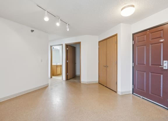an empty living room with a door to a hallway and a door into a bedroom