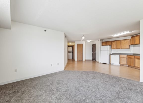 an empty living room and kitchen with white walls and wood cabinets