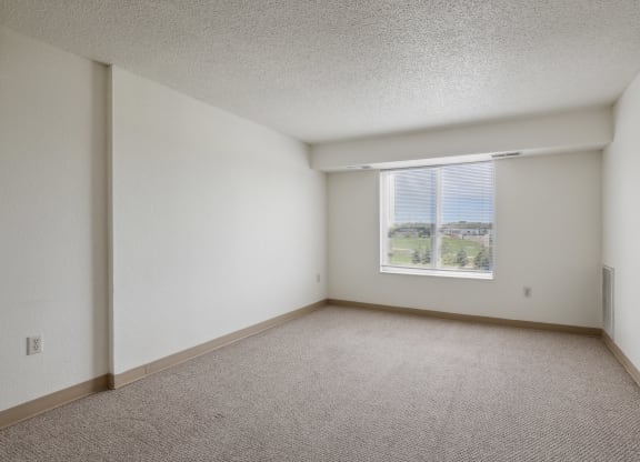 the living room of an apartment with carpet and a window