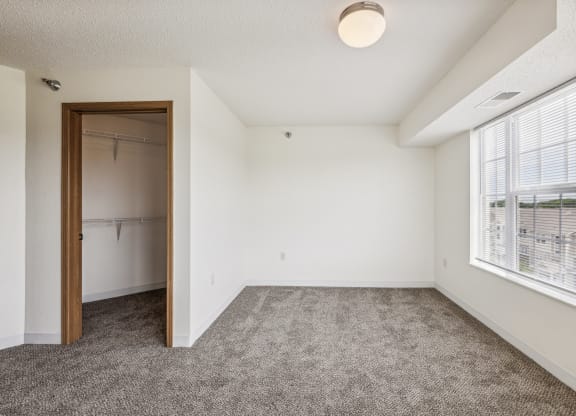 an empty room with a closet and a large window