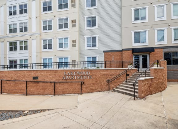 a building with stairs and a brick wall with the entrance to lakewood apartments