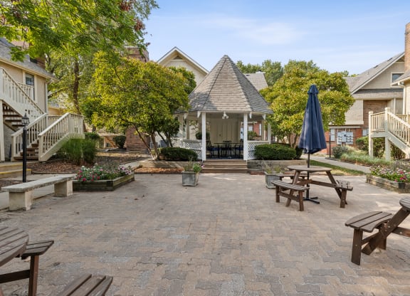 a patio with benches and tables and a gazebo