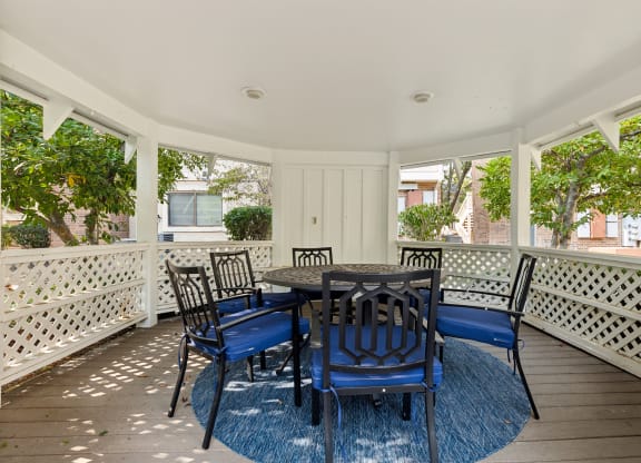 a dining room with blue chairs and a table on a porch