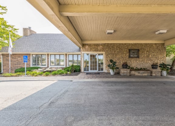 the entrance of a brick building with glass doors and a porch