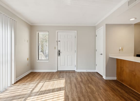 an empty living room with a white door and wood floors