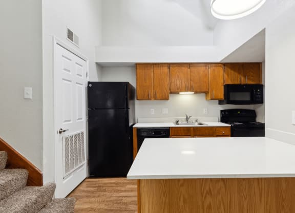 a kitchen with a white counter top and a black refrigerator