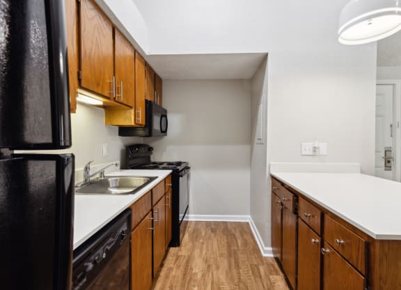 a kitchen with black appliances and wooden cabinets and white counter tops