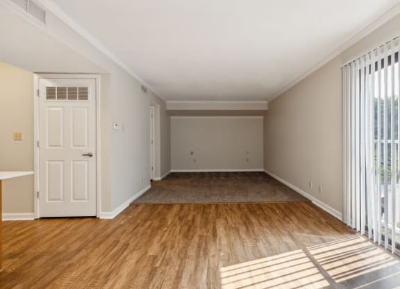 an empty living room with a white door and wood flooring