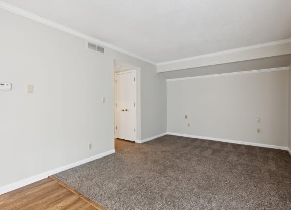 an empty living room with a rug and white walls