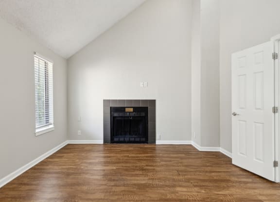 an empty living room with a fireplace and wooden floors