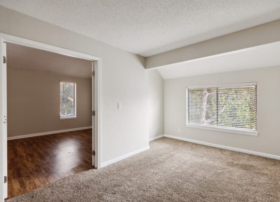 an empty living room with a window and a hard wood floor