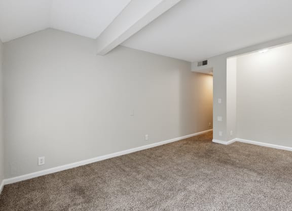an empty living room with carpet and white walls
