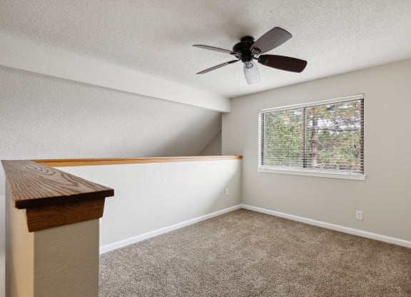 an empty bedroom with a ceiling fan and a window