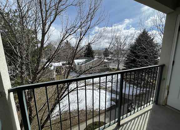 A balcony with a metal railing overlooking a snowy landscape.