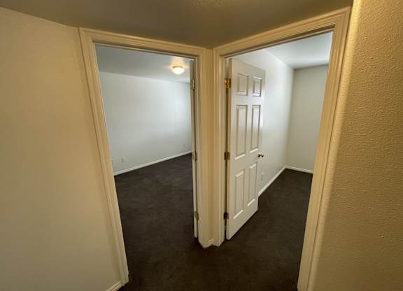 A white door is open to a room with a carpeted floor.