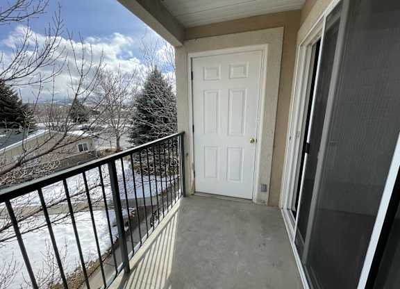 A balcony with a white door and a black railing.
